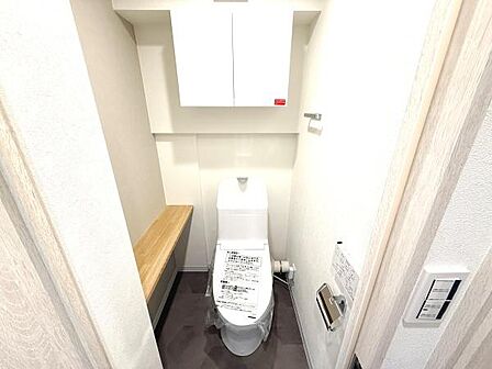 明るい色合いで清潔感のあるトイレです。収納スペースが設けられており使い勝手にも配慮されています。十分なスペースが確保され落ち着いた雰囲気です。壁面には便利な棚も設置されています。