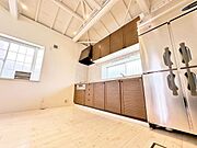 天井が高く開放感を感じるキッチンです。窓からの自然光がしっかり入り明るい空間となっています。収納スペースも豊富でキッチンの使い勝手が良いです。大型の冷蔵庫が置かれており利便性が高い仕様です。