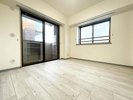 大きな窓から自然光がたっぷり差し込む明るい寝室です。シンプルな内装で家具の配置がしやすいレイアウトです。バルコニーへのアクセスもスムーズで使い勝手の良さが魅力です。ゆったりとした空間が広がっています。