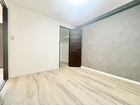 シンプルな内装が特徴の寝室です。明るいフローリングが空間を広く見せてくれます。壁の一面にアクセントカラーが使われており落ち着いた印象です。収納スペースも確保されています。清潔感のある空間です。