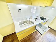 明るいカラーが印象的なキッチンです。シンクや作業スペースが広く設計されています。食器洗い機が備え付けられており日常の作業に便利です。収納もしっかりと確保されています。