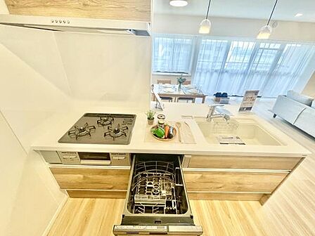 ナチュラルな木目調のキッチンが明るい印象です。備え付けの食洗機があり家事の効率化が期待できます。三口コンロがあり調理もスムーズに行えます。広々とした作業スペースで整理しやすい設計です。