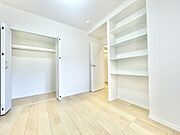 明るい色合いの床と白を基調とした壁が洋室を開放的な印象にしています。クローゼットが備え付けられており収納スペースが充実しています。壁面には便利な棚が設置されており整理整頓もはかどります。