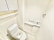 シンプルなデザインのトイレ空間です。壁付けの収納棚が設けられ整理整頓がしやすい環境です。トイレ本体と手洗いスペースが隣接しており使い勝手にも配慮されています。