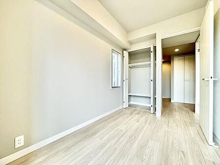 明るい色合いの床と壁が特徴的な子供部屋です。備え付きのクローゼットには収納スペースが確保されています。小窓から自然光が差し込み全体的にすっきりとした印象です。ドアは開閉しやすいデザインです。