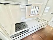キッチンは白を基調としたシンプルなデザインです。三口コンロやシンクが備わっています。カウンターが付いており開放感があります。作業スペースも確保されています。
