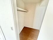 広々とした収納スペースで棚とハンガーパイプが設置されています。シンプルな内装で使い勝手にも配慮。壁面もきれいに仕上げられており収納設備が充実しています。開放感のある設計です。