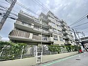 外観は落ち着いた色合いで敷地全体がフェンスと植栽で囲まれています。マンションのバルコニーも広々と設計されています。道路からのアクセスがしやすい配置です。全体的に整った外観が特徴です。
