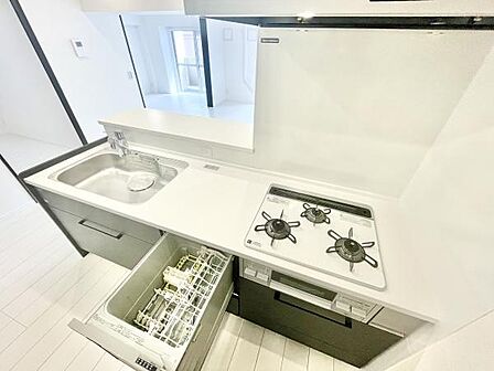 明るい色調でまとめられたキッチンは清潔感があります。食器洗い乾燥機と三口コンロが揃っています。調理や片付けの作業効率にも配慮されています。全体的に使いやすさが考えられた設計です。