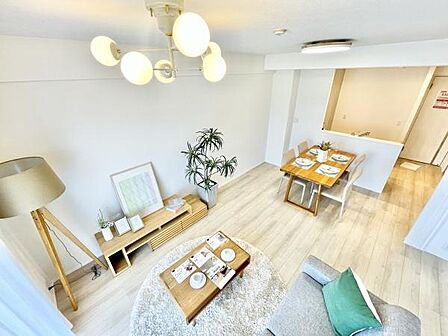 やさしい色合いの床とナチュラルな家具が特徴のリビングです。窓から明るい光が差し込み開放感があります。天井の照明や観葉植物が空間にアクセントを添えています。