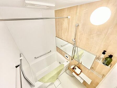 明るい照明とナチュラルな木目調パネルで清潔感のあるバス空間です。広々とした浴槽と使いやすいシャワー設備が備わっています。大型ミラーや収納棚も配置され日々のバスタイムをサポートします。