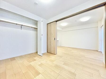 明るい色合いのフローリングが印象的な洋室です。大きなクローゼット付きで収納が充実しています。開放的な空間が広がり可動式の仕切りでレイアウトの自由度があります。窓からの光が室内に届きやすい設計です。