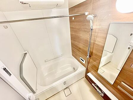 木目調のアクセントパネルが空間に明るさを与えています。清潔感のあるホワイトとナチュラルなデザインが魅力です。浴槽には手すりも設置されており安心してご利用いただけます。