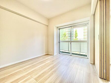 大きな窓から自然光がたっぷり差し込む明るい寝室です。清潔感のある内装で落ち着いた雰囲気が魅力です。床は木目調でお手入れもしやすい仕様です。使い勝手の良いシンプルな空間が特徴です。