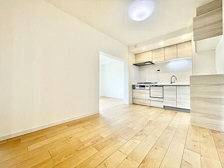明るいフローリングが特徴的なリビングです。開放感を感じる空間でキッチンとの一体感があります。全体的にシンプルなデザインで日々のお手入れもしやすいです。ナチュラルカラーの床材が落ち着いた印象を与えます。