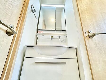清潔感のある洗面台は収納スペースも充実しています。ミラー扉が空間に明るさをプラスし使いやすい配置です。すっきりとしたデザインが印象的です。タオル掛けも便利に設置されています。