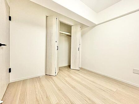 明るい色調のフローリングと白い壁が清潔感のある空間を演出しています。クローゼットが設置されているので収納も確保されています。扉や天井のシンプルなデザインがすっきりとした印象を与えます。