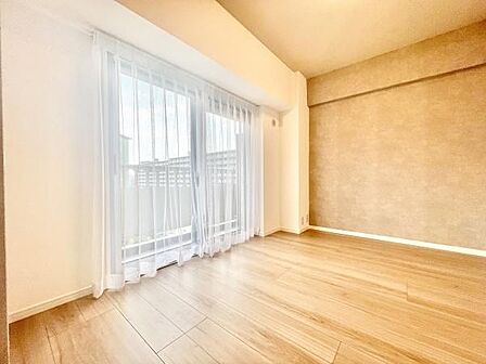 大きな窓から光がしっかりと入る洋室です。明るい床材と壁面が室内に開放的な印象を与えます。白を基調とした空間はコーディネートもしやすいです。カーテンの透け感も爽やかに映えます。