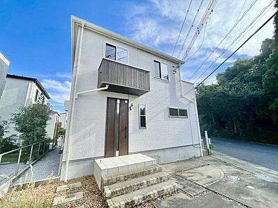 外観：白を基調とした外観が印象的な住まいです。玄関前には広めのアプローチスペースがあります。シンプルで落ち着いたデザインが特徴です。バルコニー付きで採光も期待できます。周辺は自然が多く静かな環境です。