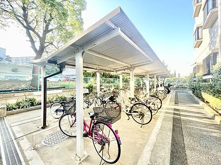 屋根付きの駐輪場が完備されています。複数台の自転車を置くスペースがあります。敷地内にあり利用しやすい位置に設置されています。建物横に隣接しています。整理されたレイアウトが特徴です。