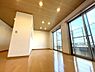 室内：大きな窓から、心地よい光と風をたっぷり取り込める明るいリビング。美しい木目調の天井とダウンライトがスタイリッシュな空間を演出し、家族でゆったりとくつろげる開放的な住まいです。