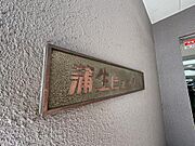 「（蒲生ビューハイツ）」重厚感のある館銘板が設置されたエントランス。セコムの防犯カメラ設置マークも見え、セキュリティ面への配慮が伺えます。細部まで管理が行き届いた、安心感のある住まいです。
