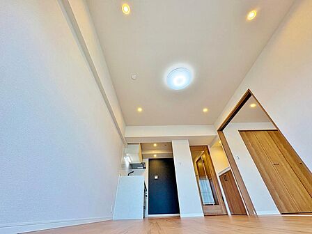 白壁に映える木目調の建具が美しい、リビングから見た風景。折り上げ天井に配された照明が空間に奥行きと上品なニュアンスをプラスし、くつろぎのひとときを演出します。
