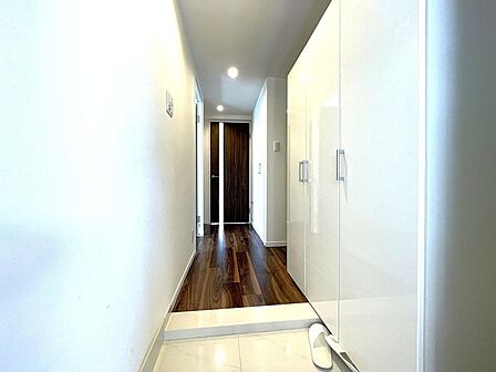 白を基調としたクロスと大容量の白い玄関収納が爽やかさを演出する玄関。深みのあるダークブラウンのフローリングが上質な空間を醸し出し、落ち着きと高級感あふれる印象を与えます。