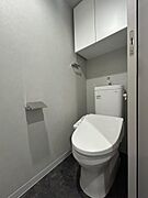 温水洗浄機能付きトイレを採用。上部には吊り戸棚を設け、トイレットペーパーや日用品の収納にも困りません。グレー系のシックな内装が空間全体に落ち着いた雰囲気をもたらしています。
