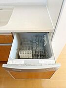 キッチンには食器洗浄機が備え付けられています。手間を省くうえ衛生面にも配慮された設備です。収納スペースも確保されています。シンプルなデザインで日常使いに適しています。