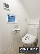 白を基調とした明るいトイレです。換気窓があり自然な明るさが確保されています。ペーパーホルダーや手洗い付きの仕様が使いやすさを感じさせます。壁のデザインもシンプルで清潔感があります。