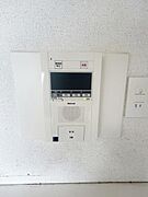 壁に設置されたインターホンシステムが備わっています。モニター付きで来訪者の確認がしやすい仕様です。操作ボタンが分かりやすく配置されています。壁のコンセントと一体でスマートな見た目です。