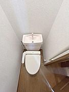 シンプルな造りで清潔感のあるトイレです。手洗い付きタンクが備わっています。空間を有効に使った配置がされています。温水洗浄便座も設置されています。