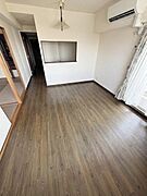【一部AIモノ消し済み・実際の室内状況優先】リビングはナチュラルなフローリングが特徴で窓からの採光がしっかり確保されています。エアコンが設置されており快適に過ごせます。