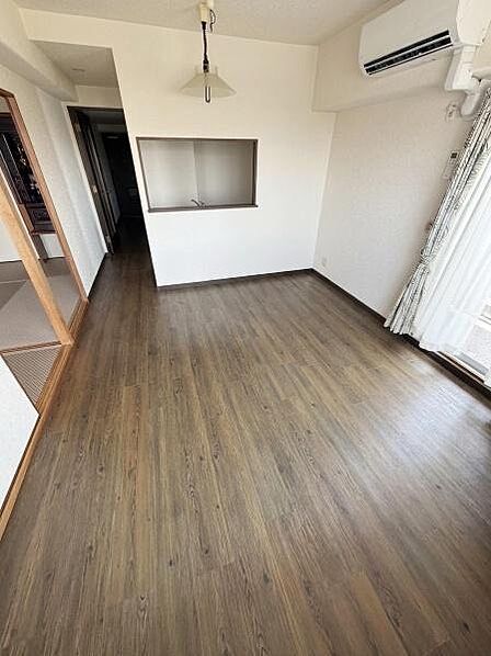 【一部AIモノ消し済み・実際の室内状況優先】リビングはナチュラルなフローリングが特徴で窓からの採光がしっかり確保されています。エアコンが設置されており快適に過ごせます。