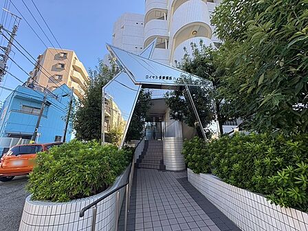 青空の下、丁寧に手入れされた植栽と洗練されたアプローチが穏やかな日常の始まりを予感させます