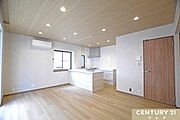 【LDK12.25帖】木目調の天井とフローリングが温かみを演出する12.25帖のLDK。リビングとキッチンが一体となった設計で、ご家族との会話を楽しみながら心地よく過ごせます。
