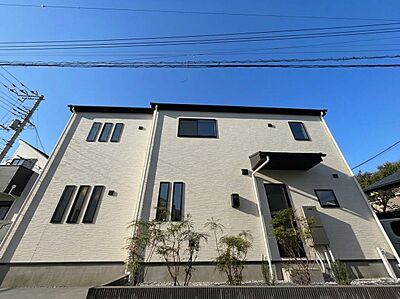 外観:白い外壁の2階建て住宅と前面道路 外観:白い外壁の2階建て住宅と前面道路