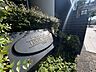 外観：植栽に囲まれた物件名の案内プレート