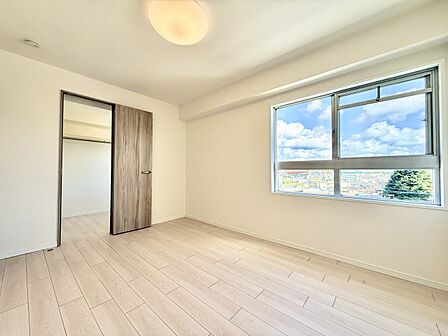 明るい窓と木目調の床が特徴の洋室です