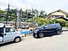 周辺：住宅街の道路沿いに駐車された車と周辺の住宅が見えます
