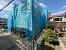 外観：青い養生シートで覆われた建物と植栽