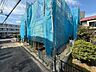 外観：青い養生シートで覆われた建物と周辺の道路