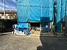 外観：青い養生シートで覆われた建物と舗装された敷地