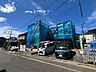 外観：青いネットで覆われた建築中の建物と前面道路
