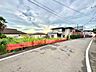 周辺：道路沿いの建物と赤いフェンスが見える周辺の景観