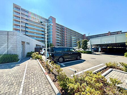集合住宅と敷地内の歩道・植栽、駐車場を望む外観
