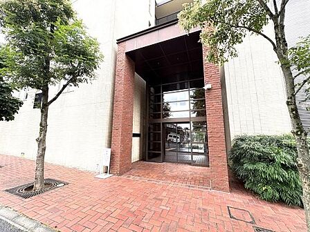 天井高く開放感あるエントランス。白い外壁にレンガ色のタイルが映える、高級感ある佇まいです。
