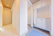 白を基調とした清潔感あふれる玄関。天井の木目調アクセントが温もりをプラスし、収納力も備えた快適な空間です。