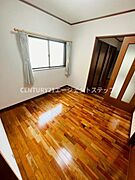 明るい窓から自然光が差し込む洋室です。美しい木目調のフローリングが落ち着いた印象を与えます。収納スペースも充実しておりお部屋をすっきりと保てます。ドアのガラス部分が空間にアクセントを加えています。